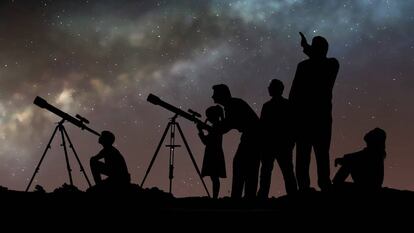 Un grupo de personas mira las estrellas con telescopios.