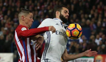 Nacho del Real Madrid para el balón con el pecho ante la presencia de Fernando Torres del Atlético de Madrid.
