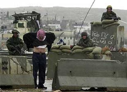 Tres soldados israelíes registran a un palestino en el control de Kalandia, antes de entrar a Ramala.