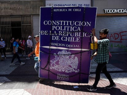 Un hombre trasporta un cartel con la imagen de la actual Constitución chilena, en Santiago, el 12 de noviembre de 2019.