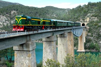 El tren atraviesa el pantano de Cellers, con apariencia de lago natural, en cuyo espejo de aguas tranquilas se reflejan los exuberantes bosques de ribera y las cumbres pirenaicas.