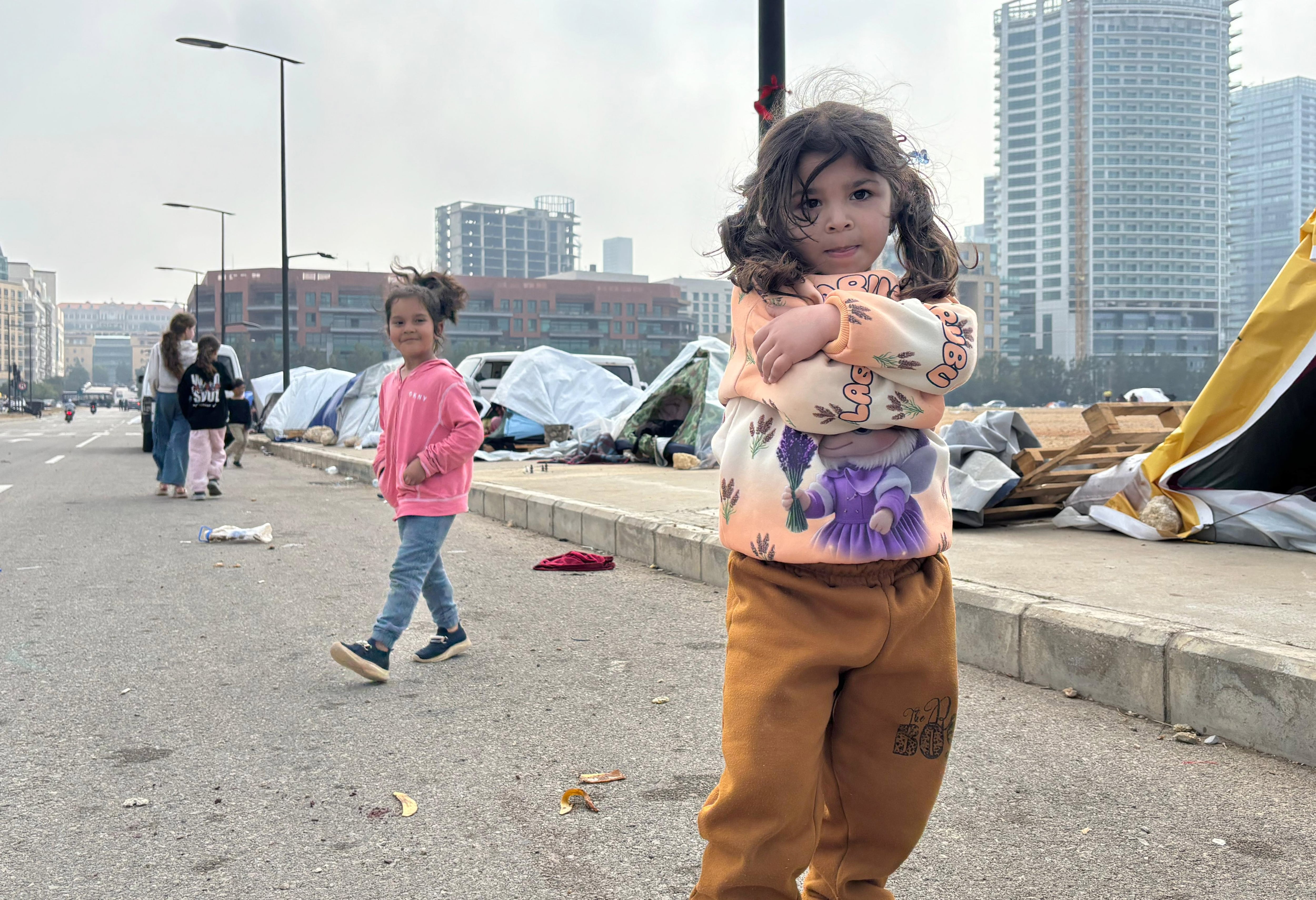 Unas niñas pasan el rato ante la tienda de campaña donde están forzosamente desplazas junto a sus familias por la ofensiva israeí.