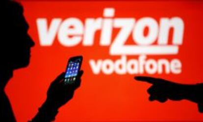 Silueta de dos hombres frente a un cartel de Verizon