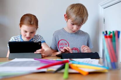 Dos niños realizan tareas escolares a través de sus tabletas electrónicas. 