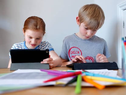 Dos niños realizan tareas escolares a través de sus tabletas electrónicas. 