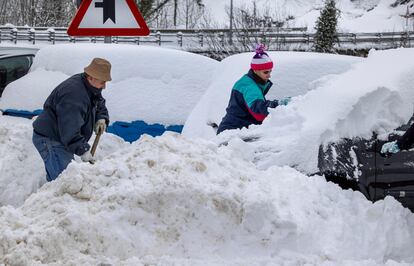 Unos vecinas tratan de quitar la nieve de sus vehiculos en el pueblo de Pajares, a principios de esta semana.