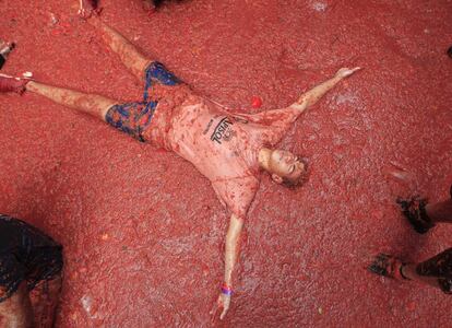 Un joven se echa al suelo lleno de tomate tras la batalla de la Tomatina.