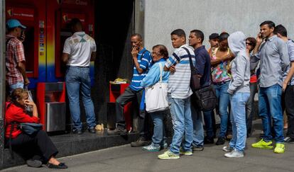 Venezolanos hacen cola para sacar dinero en Caracas, este jueves.
