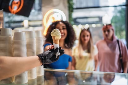 Un empleado entrega a un cliente un cono de helado.
