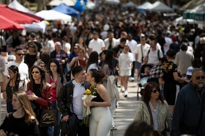 Una pareja con un ramo de rosas se da un beso en la Rambla de Barcelona.