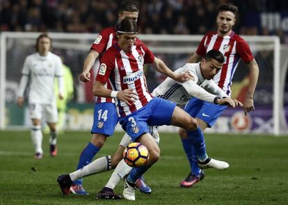 El portugués Cristiano Ronaldo (d), del Real Madrid, lucha el balón con el defensa brasielño del Atlético de Madrid Filipe Luis (i).