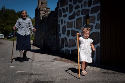 Una mujer de 95 años pasea junto a una de sus bisnietas en la aldea de San Xurxo (Ourense), el pasado verano.
