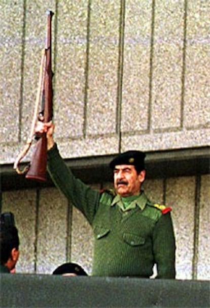 Sadam Husein dispara un fusil durante un desfile militar en Bagdad.