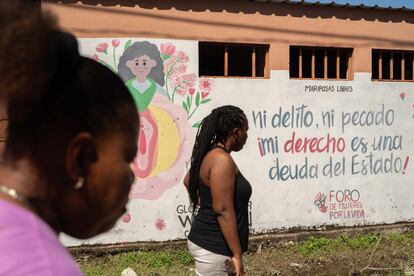 Dos miembros de la organización Mariposas Libres transitan frente a un mural que ellas mismas gestionaron, en la comunidad de Tornabé (Honduras).