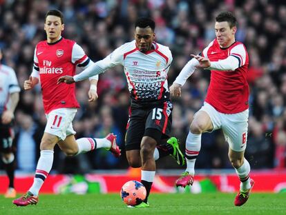 Daniel Sturridge, del Liverpool trata de escapar con el balón. Detrás, Özil y Laurent Koscielny, de Arsenal.