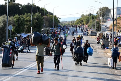 Migrantes del campo incendiado de Moria caminan hacia una nueva ubicación en la isla griega de Lesbos, el jueves.