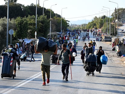 Migrantes del campo incendiado de Moria caminan hacia una nueva ubicación en la isla griega de Lesbos, el jueves.