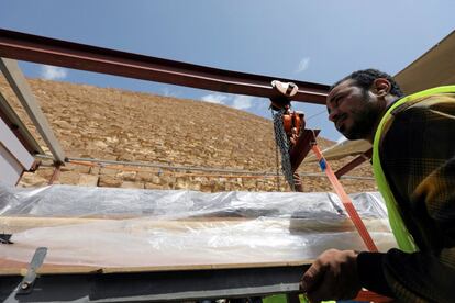 Un trabajador transporta un segmento de madera del suelo donde fue descubierta antes de llevarlo al laboratorio, en Giza (Egipto).