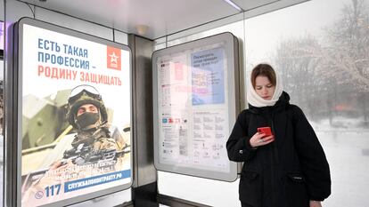 Una mujer junto a un cartel que llama al reclutamiento en una parada de autobús en Moscú, el 17 de diciembre de 2023.