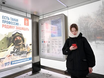 Una mujer junto a un cartel que llama al reclutamiento en una parada de autobús en Moscú, el 17 de diciembre de 2023.