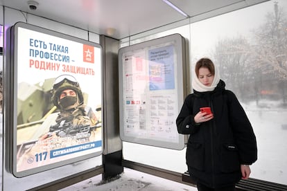 Una mujer junto a un cartel que llama al reclutamiento en una parada de autobús en Moscú, el 17 de diciembre de 2023.