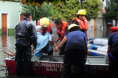 Una mujer es evacuada por un cuerpo de bomberos hoy, miércoles 3 de abril de 2013, en La Plata (Argentina). Al menos 31 personas han muerto en la capital argentina y en la provincia de Buenos Aires a causa de un fuerte temporal de lluvias.