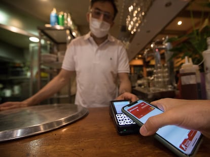 El cliente de un bar paga con su teléfono en un datáfono.