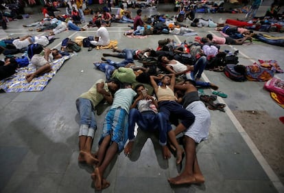 Varios grupos de pasajeros descansan dentro de una estación de tren de Calcuta tras la cancelación de los trenes entre Calcuta y Odisha, este viernes.