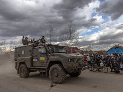 Unos soldados ucranios saludan desde un vehículo militar a los residentes que esperan en una cola para recibir ayuda humanitaria, en la ciudad de Trostyanets, Ucrania, el 29 de marzo de 2022.