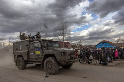 Unos soldados ucranios saludan desde un vehículo militar a los residentes que esperan en una cola para recibir ayuda humanitaria, en la ciudad de Trostyanets, Ucrania, el 29 de marzo de 2022.