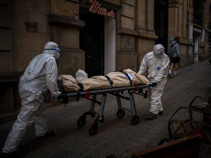 Empleados de una funeraria trasladan el cadáver de un anciano fallecido por covid en una residencia de Barcelona, el 13 de noviembre.