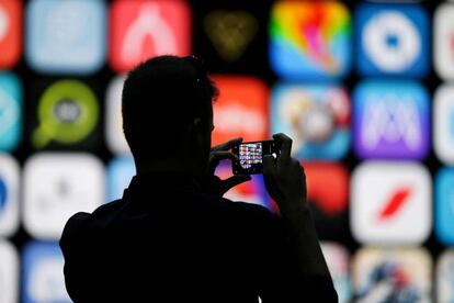 FILE PHOTO: A visitor uses his iPhone X to take photos of the stage at the Apple Worldwide Developer conference (WWDC) in San Jose