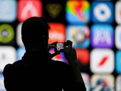 FILE PHOTO: A visitor uses his iPhone X to take photos of the stage at the Apple Worldwide Developer conference (WWDC) in San Jose