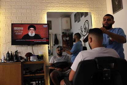 Varias personas en una barbería observaban por televisión la intervención de Hasan Nasrallah, líder de Hezbolá, este viernes en Beirut (Líbano).