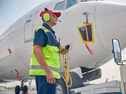 Un trabajador aeroportuario con auriculares para proteger sus oídos del ruido de los aviones.