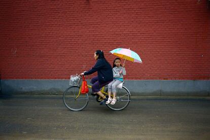 Una niña y su madre vuelven a casa en bicicleta después de la escuela en Pekín, China.