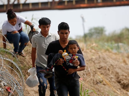 Inmigrantes caminan al lado de un alambre de púas en Eagle Pass, en la frontera entre Texas y México, el 22 de mayo.
