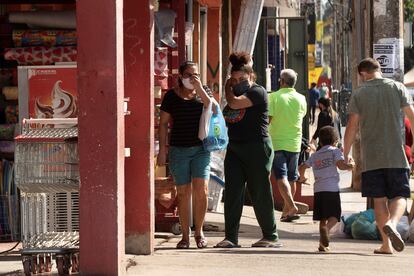 Pessoas utilizando máscaras fazem compras neste sábado em  uma rua de Brasília.