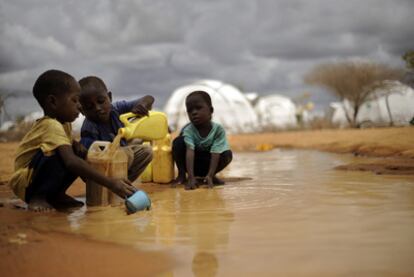 Niños somalíes recogen  agua de una charca en el campo  de refugiados de Dadaab, en Kenia.