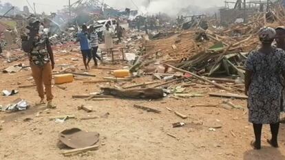 Un grupo de personas camina junto a los restos dejados tras la explosión de un camión en Ghana.