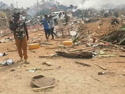 Un grupo de personas camina junto a los restos dejados tras la explosión de un camión en Ghana.