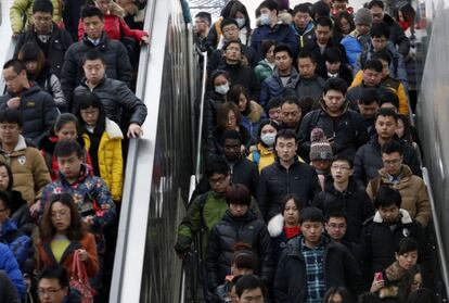 Vuelta al trabajo en China. Decenas de personas descienden por una escalera mecánica para acceder al metro en hora punta en Pekín en el primer día laborable tras las vacaciones del inicio del Año Nuevo chino.