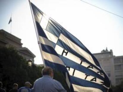 Un militar retirado ondea una bandera griega mientras participa en una protesta por las calles de Atenas. EFE/Archivo