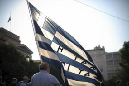 Un militar retirado ondea una bandera griega mientras participa en una protesta por las calles de Atenas. EFE/Archivo