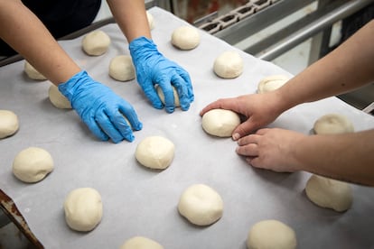 Dos mujeres moldean los bollos de los panes de hamburguesas en el obrador Juanito Baker.