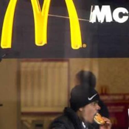 Un cliente come una hamburguesa en un restaurante de McDonalds.