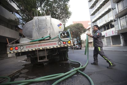 El operador de una pipa llena la cisterna de un edificio a petición de los vecinos.