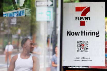 A 7-Eleven convenience store has a sign in the window reading "Now Hiring" in Cambridge, Massachusetts