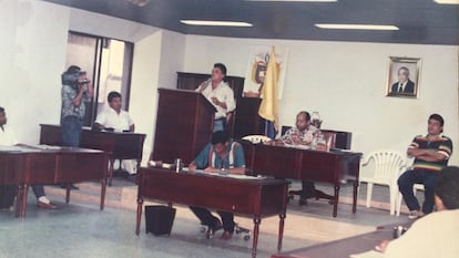 Luis López Peralta es quien está de pie frente a un atril hablando por micrófono y Kiko Gómez es la persona sentada en el costado derecho, de brazos cruzados.