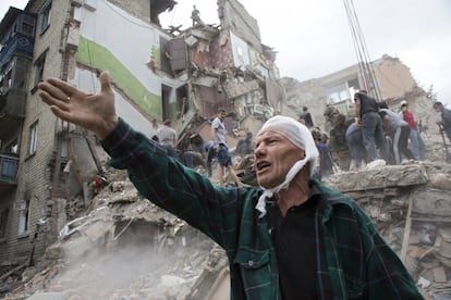 Igor Chernetsov, whose wife was killed in a building demolished by an airstrike, gestures near the collapsed structure in Snizhne, 100 kilometers east of Donetsk, eastern Ukraine, Tuesday, July 15, 2014. At least nine civilians were killed in the attack, rescue workers said, adding to the steadily growing number of civilians killed over four months in a dogged pro-Russian insurgency. Government officials denied the Tuesday strike was carried out by Ukraine's air force. (AP Photo/Dmitry Lovetsky)